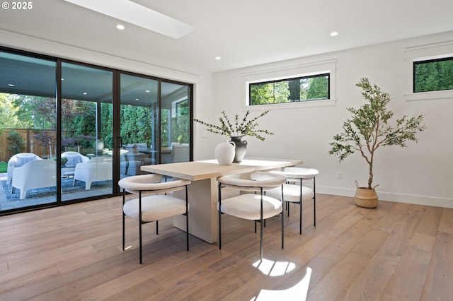 dining area featuring light wood-style flooring, a skylight, baseboards, and recessed lighting