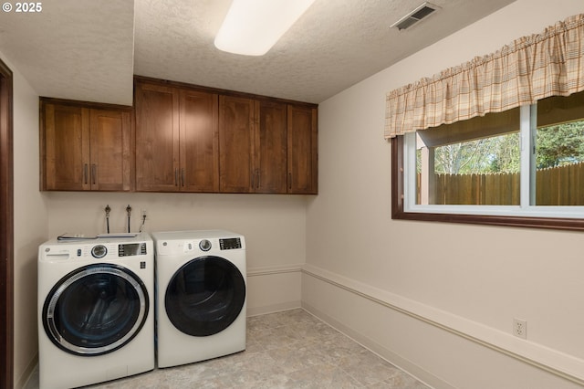 laundry area with visible vents, washing machine and dryer, baseboards, cabinet space, and a textured ceiling