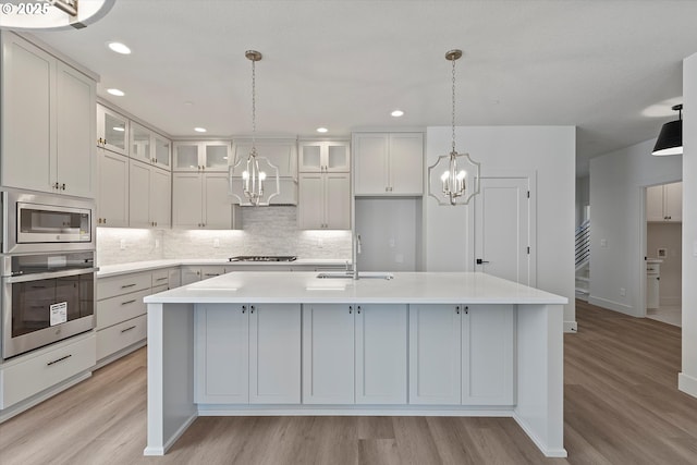 14196 SE Iseli Ln, Clackamas, OR 97015 - kitchen featuring stainless steel appliances, a chandelier, light wood-style floors, light countertops, and decorative backsplash