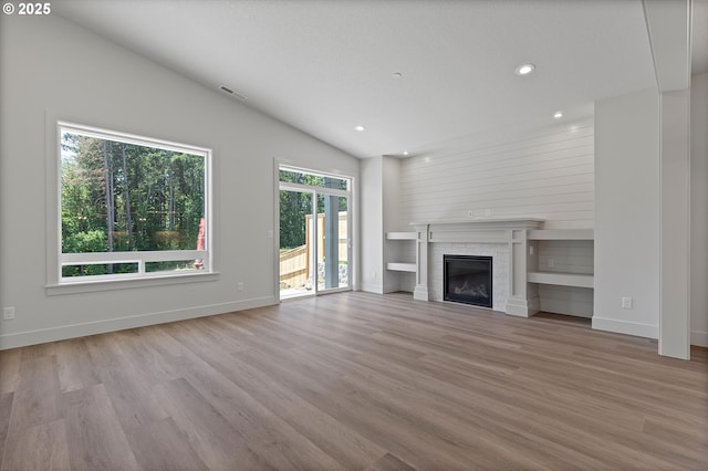14196 SE Iseli Ln, Clackamas, OR 97015 - unfurnished living room with vaulted ceiling, wood finished floors, a glass covered fireplace, and recessed lighting