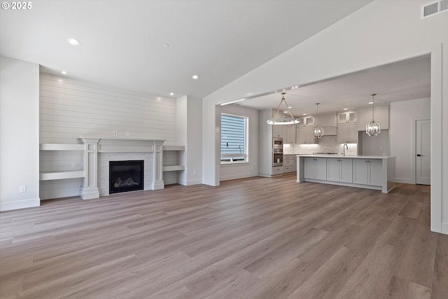14196 SE Iseli Ln, Clackamas, OR 97015 - unfurnished living room with recessed lighting, vaulted ceiling, light wood-style flooring, and a fireplace