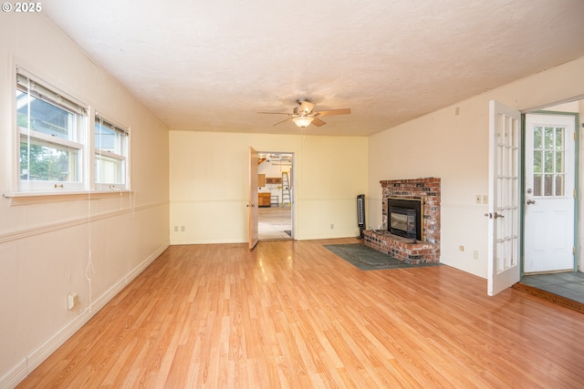 2822 Crocker Rd, Eugene, OR 97404 - unfurnished living room with light wood-style flooring, ceiling fan, a fireplace, and a textured ceiling