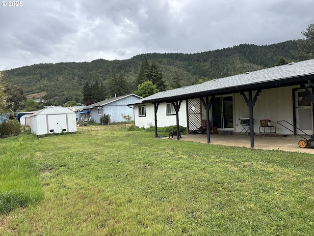 145 Donald Ter, Myrtle Creek, OR 97457 - view of grassy yard featuring a patio area, a forest view, a storage shed, a mountain view, and an outdoor structure