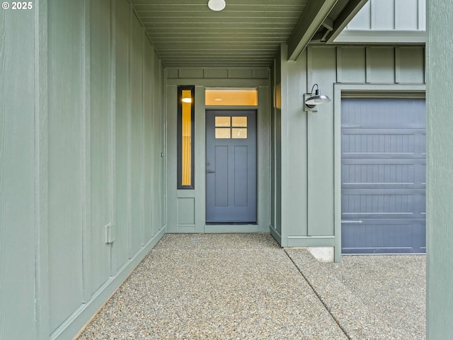 view of exterior entry featuring an attached garage and board and batten siding