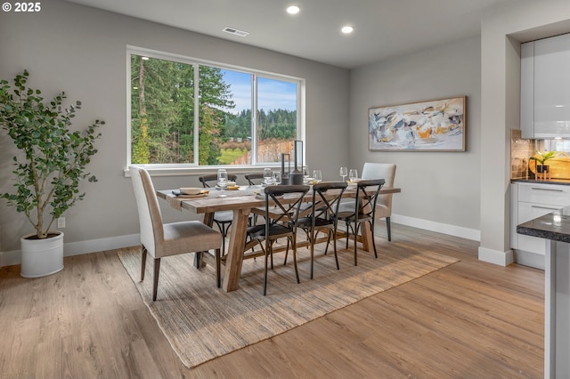 dining space featuring light wood-type flooring, visible vents, and baseboards