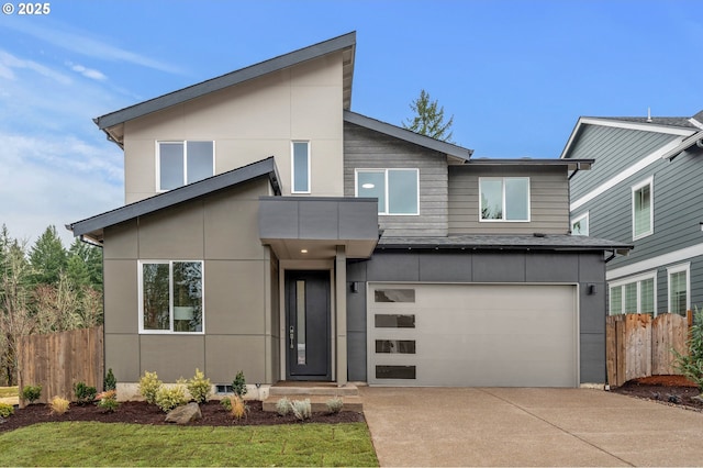 contemporary house with a garage, concrete driveway, and fence