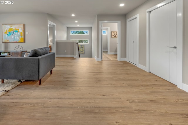 corridor featuring baseboards, recessed lighting, an upstairs landing, and light wood-style floors