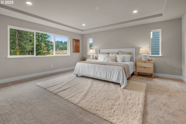 bedroom featuring light carpet, a tray ceiling, recessed lighting, and baseboards