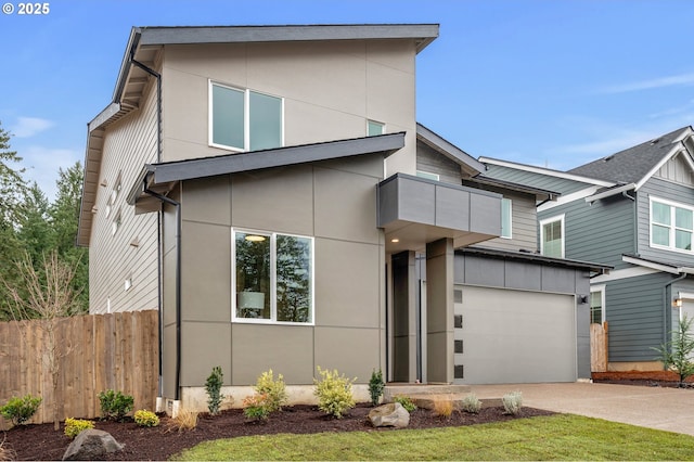 contemporary home featuring a garage, driveway, fence, and stucco siding