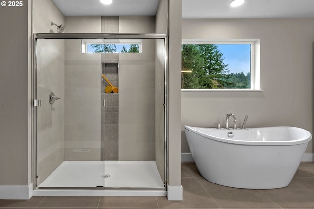 bathroom with baseboards, a freestanding tub, a shower stall, and tile patterned floors