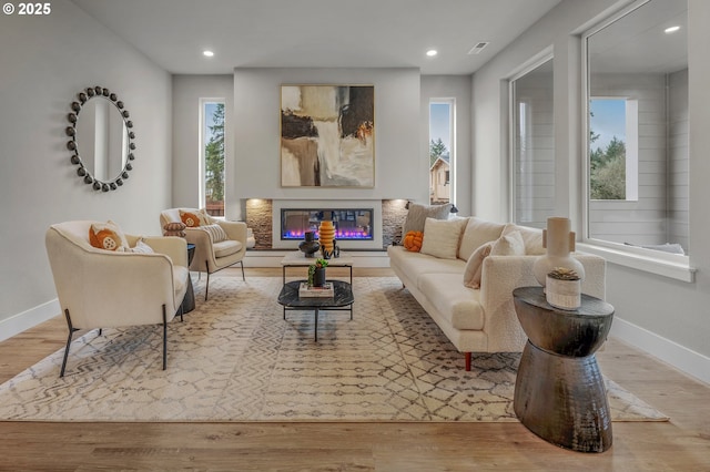 living area featuring recessed lighting, baseboards, wood finished floors, and a glass covered fireplace