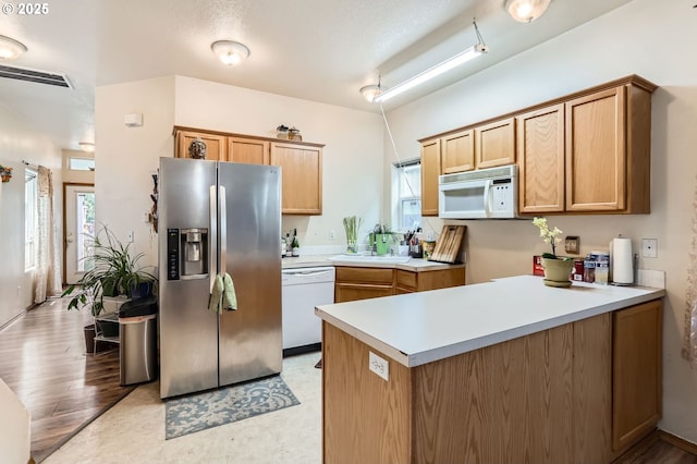 kitchen with plenty of natural light, visible vents, white appliances, and a peninsula