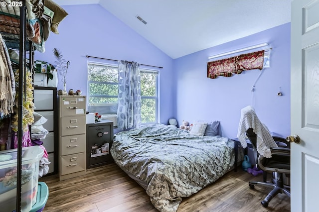 bedroom with visible vents, lofted ceiling, and wood finished floors