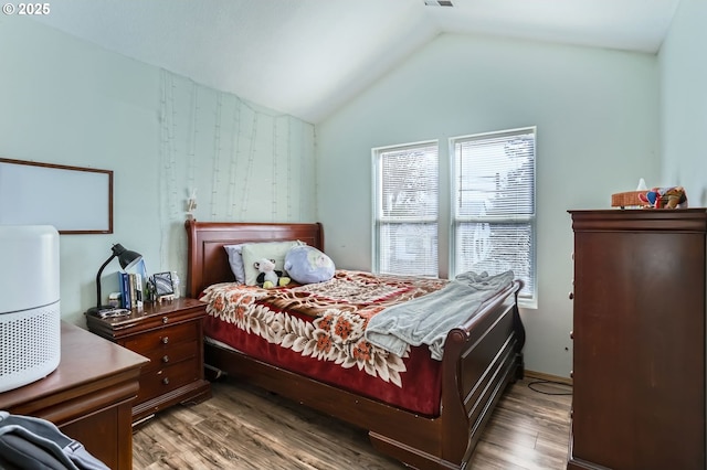 bedroom with wallpapered walls, lofted ceiling, and wood finished floors