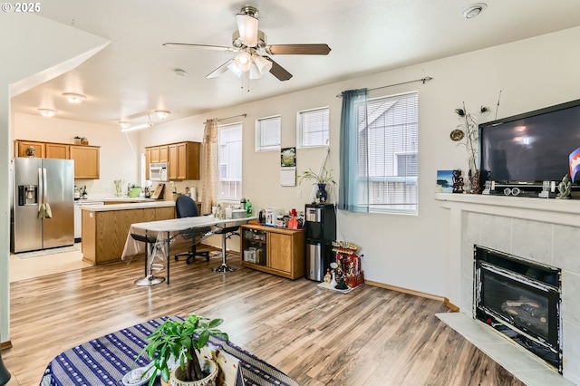 office space with light wood-type flooring, baseboards, a fireplace, and a ceiling fan