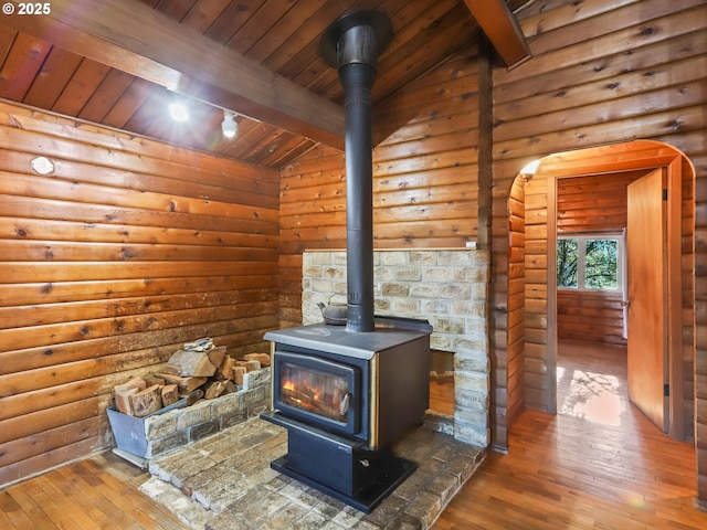 room details featuring beamed ceiling, wooden ceiling, hardwood / wood-style flooring, and a wood stove