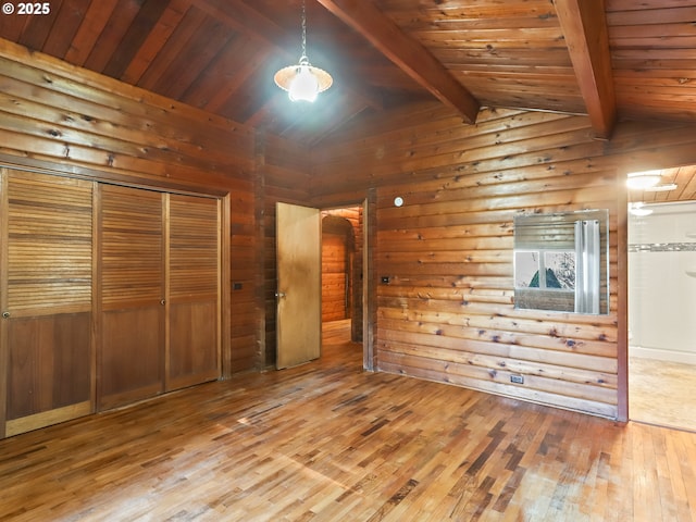 unfurnished bedroom featuring hardwood / wood-style flooring, lofted ceiling with beams, wooden ceiling, and wood walls