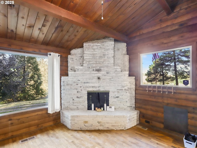 unfurnished living room with a brick fireplace, wood ceiling, vaulted ceiling with beams, and light hardwood / wood-style floors