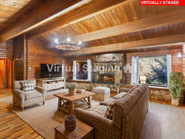 living room featuring a stone fireplace, hardwood / wood-style floors, a notable chandelier, and wooden walls