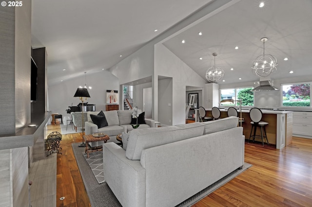 7100 SW Willowmere Dr, Portland, OR 97225 - living area featuring recessed lighting, light wood finished floors, a chandelier, high vaulted ceiling, and stairway
