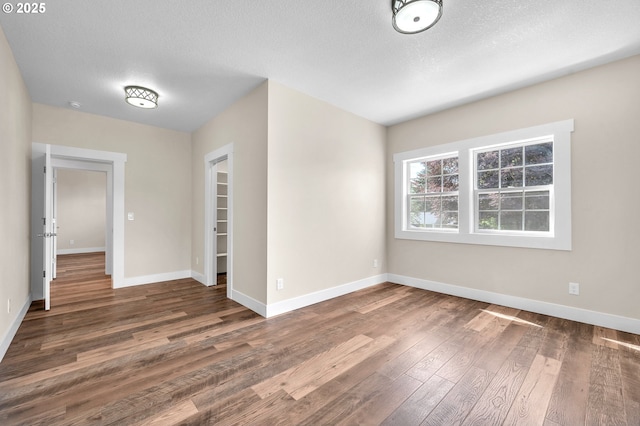 spare room featuring a textured ceiling and dark hardwood / wood-style flooring