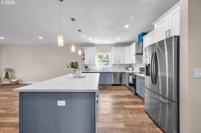 kitchen featuring decorative light fixtures, a center island, white cabinets, and appliances with stainless steel finishes