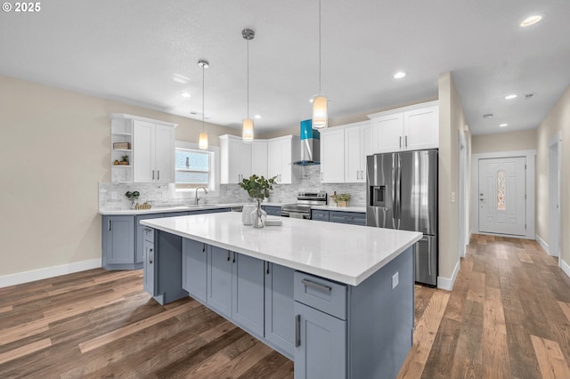 kitchen featuring white cabinetry, wall chimney range hood, stainless steel appliances, and sink