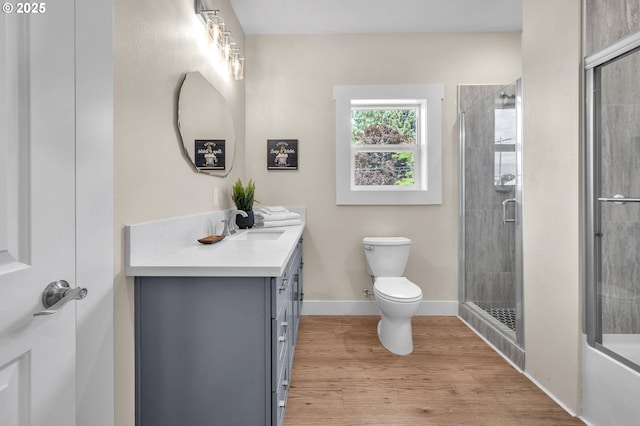 full bathroom featuring vanity, hardwood / wood-style flooring, bath / shower combo with glass door, and toilet