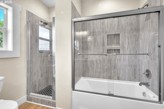 bathroom featuring hardwood / wood-style floors, shower / bath combination with glass door, and toilet