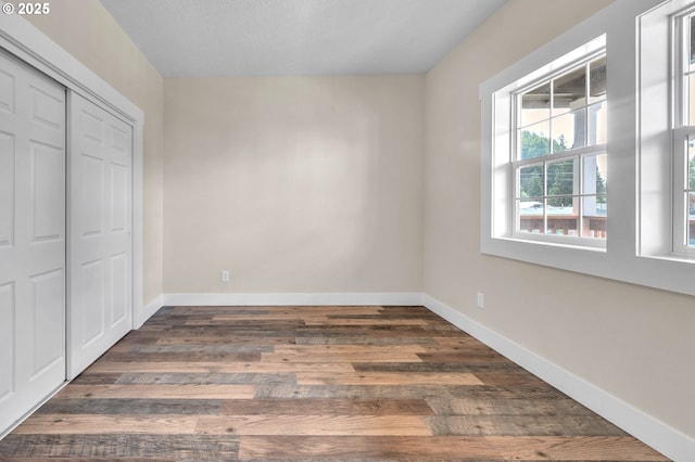 unfurnished bedroom with dark wood-type flooring and a closet