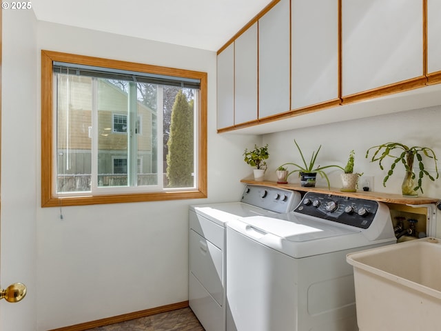 washroom with washer and clothes dryer, a sink, cabinet space, and baseboards