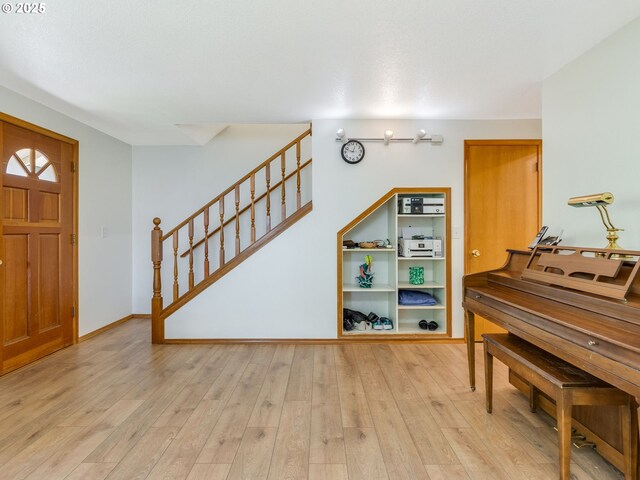 entrance foyer with light wood-style floors, baseboards, and stairway