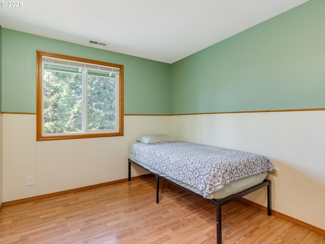 bedroom featuring wood finished floors, visible vents, and baseboards