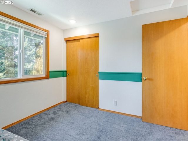 unfurnished bedroom with carpet floors, a closet, visible vents, and baseboards