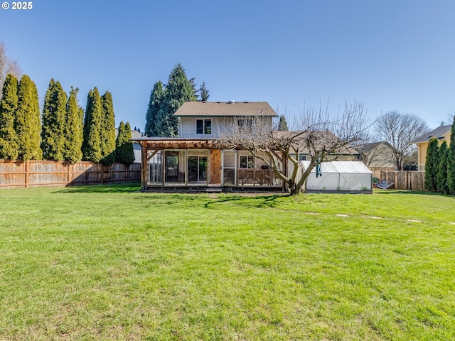 back of house with an outbuilding, a yard, a greenhouse, and a fenced backyard