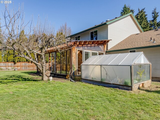 rear view of property featuring fence, an outbuilding, a lawn, and an exterior structure