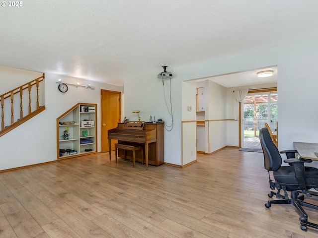 office featuring light wood-style floors, baseboards, and a textured ceiling