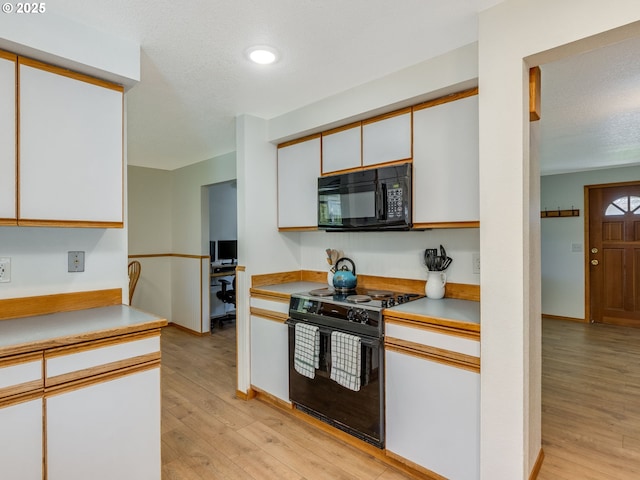 kitchen featuring light countertops, white cabinetry, a textured ceiling, light wood-type flooring, and black appliances