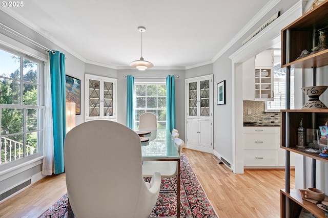 dining area with light wood-style flooring, ornamental molding, and baseboards