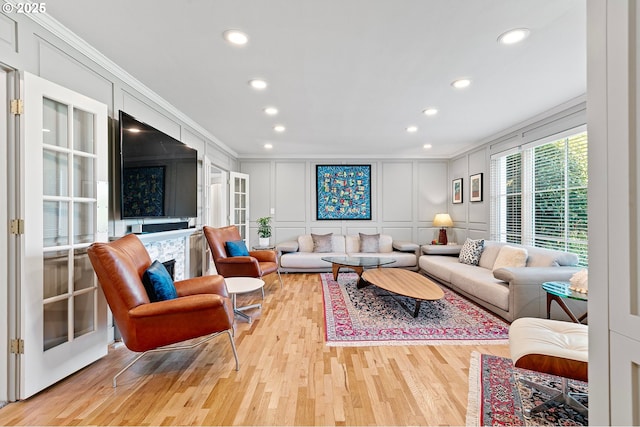 living room featuring a decorative wall, crown molding, recessed lighting, and light wood-style flooring