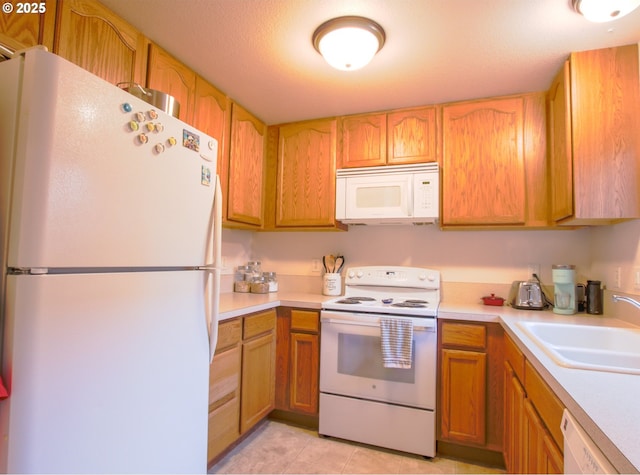 kitchen featuring a textured ceiling, light tile patterned floors, sink, and white appliances