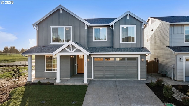 view of front facade featuring a shingled roof, concrete driveway, an attached garage, board and batten siding, and fence