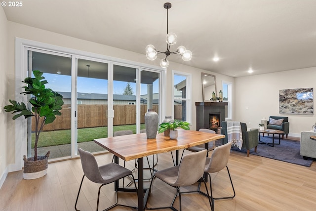 dining space featuring a chandelier, a fireplace, and light wood-style flooring