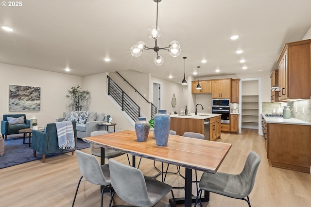 dining space with a notable chandelier, stairway, light wood-style flooring, and recessed lighting