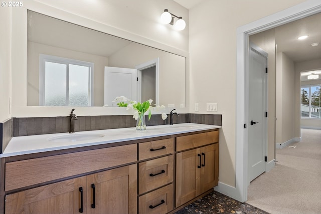 bathroom featuring double vanity, a sink, and baseboards