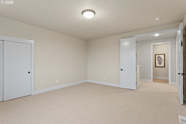 unfurnished bedroom featuring a closet, light carpet, and baseboards