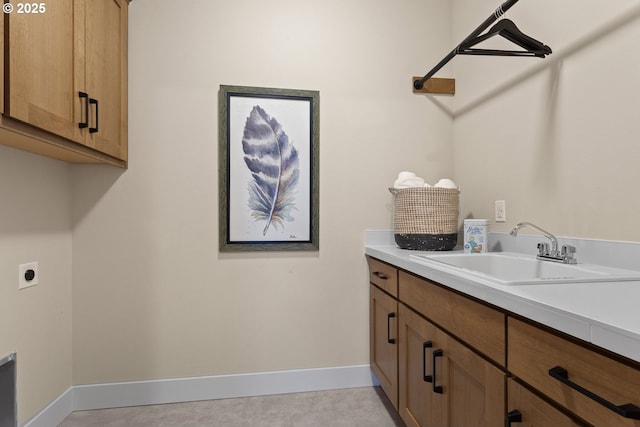 laundry room featuring baseboards, a sink, cabinet space, and hookup for an electric dryer