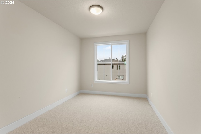 empty room featuring baseboards and light colored carpet