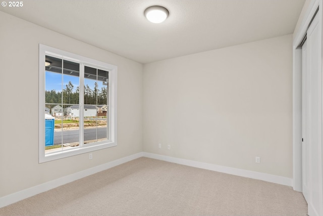 unfurnished bedroom featuring a closet, light colored carpet, and baseboards