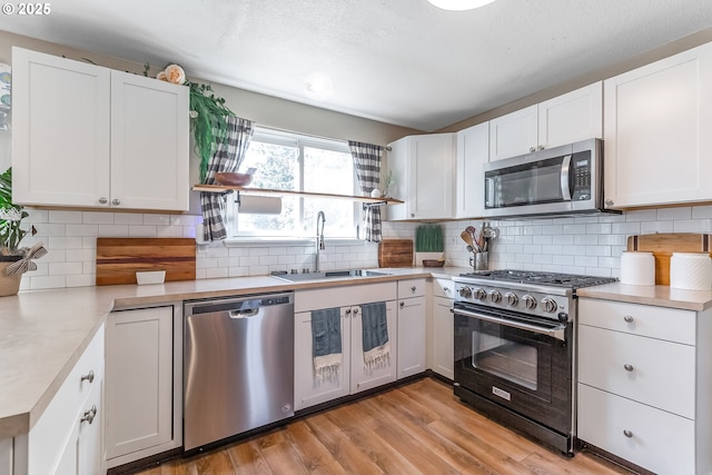 13503 NE 80th Cir, Vancouver, WA 98682 - kitchen with stainless steel appliances, light countertops, light wood-style flooring, white cabinetry, and backsplash